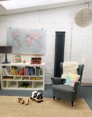 bedroom two with book shelf and cosy chair next to it and white washed walls